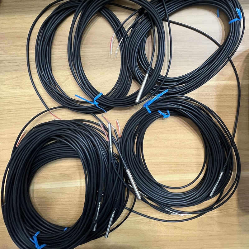 Close-up view of the temperature sensors, highlighting the cable ends and metal probes on the wooden background.