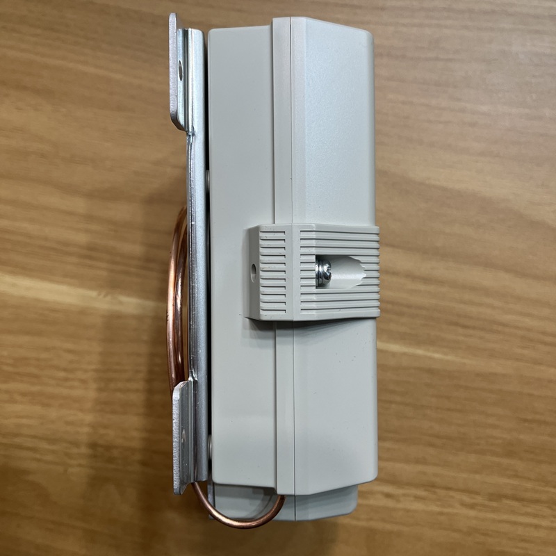 Side view of unit, built-in copper temperature sensing capillary and fixing clip visible