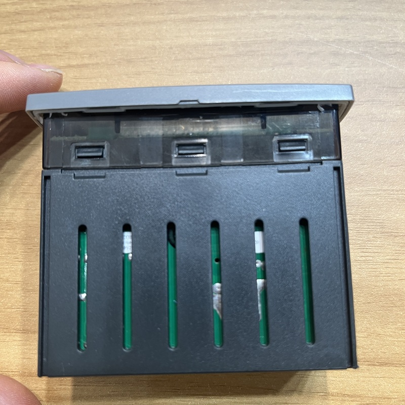 Thermostat bottom view, green circuit board inside black housing and 6 sets of vertical terminal slots